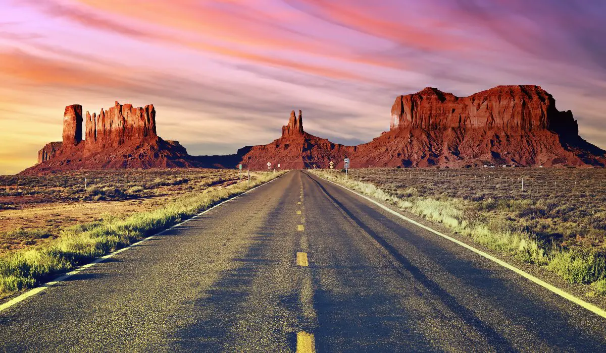 A road with mountains in the background and sunset